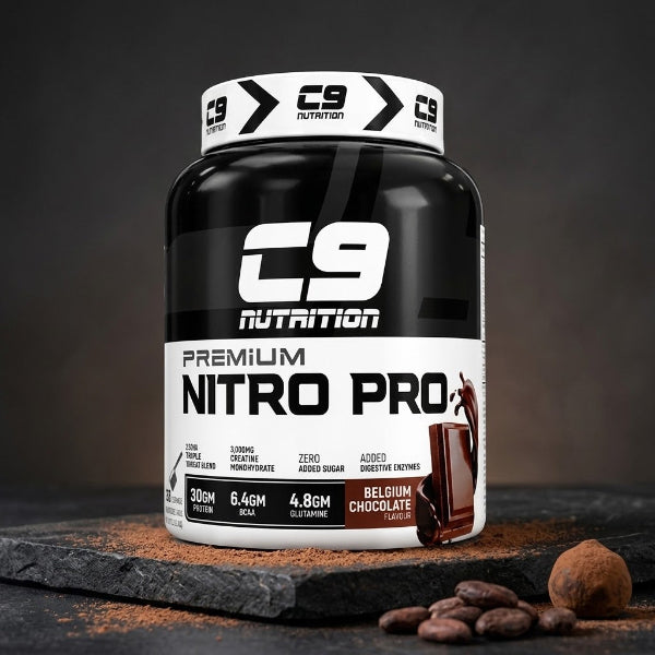 A tub of C9 Nutrition Nitro Pro+ pre-workout supplement in Belgium Chocolate flavor, displayed on a dark slate surface with cocoa powder and chocolate pieces.